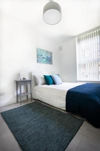 a bedroom with a bed with a blue blanket and a rug at Trustay Serviced Apartments - Shoreditch in London