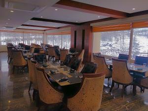 a dining room with tables and chairs and windows at The Allure Grand - Riverside Resort & Spa in Manāli