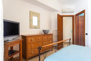 a bedroom with a television and a dresser with a bed at Villa Isabella in Porto San Paolo