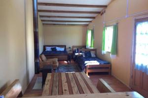 a room with two beds and a table and a couch at Beautiful cabin in Patagonia Chile. in Chile Chico