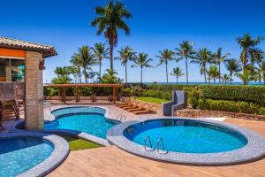 un patio trasero con piscina y un patio con palmeras en Quinta do Sol Praia Hotel, en Porto Seguro