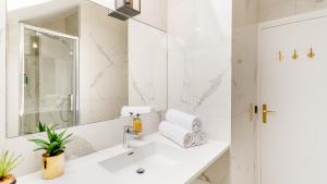 a white bathroom with a sink and a mirror at Luxury 2 Bedroom Duplex - Beautiful Monument View in Paris