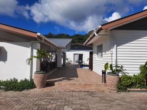 una casa con una pasarela de ladrillo entre dos edificios en Hotel Plein Soleil, en Grand Anse