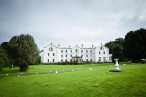 a white house with two white sheep grazing in the grass at Court Colman Manor in Bridgend