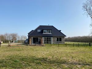 een huis met een zwart dak op een veld bij Logies Boszicht Texel in De Koog