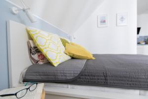 a bed with yellow pillows and a book on a table at Apartamenty Pomona in Niechorze