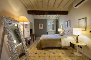 a bedroom with a large bed and a mirror at Il Battistero Siena Residenza d'Epoca in Siena