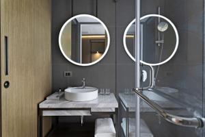 a bathroom with a sink and two mirrors at The Crescent in Panaji