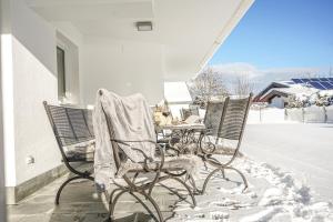 a table and chairs covered in snow on a porch at Ferienhaus Au Villa in Söll +16 photos