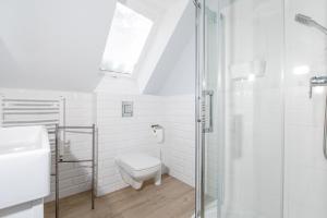a white bathroom with a toilet and a shower at Apartamenty Pomona in Niechorze