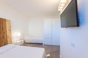 a white room with two beds and a flat screen tv at Agriturismo Umbrian Sunrise in Cannara