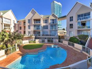 an apartment complex with a swimming pool in front of a building at Summerseas Units in Summerstrand