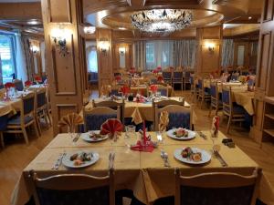 een eetkamer met tafels en stoelen en een kroonluchter bij Hotel Diamant Park in Campitello di Fassa