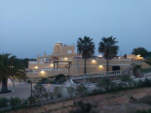 een groot gebouw met palmbomen ervoor bij Quinta Nova Vale Del Rey in Carvoeiro