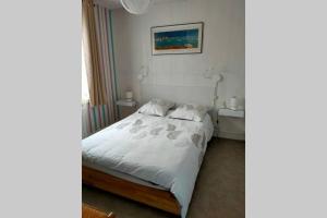 ein Schlafzimmer mit einem weißen Bett mit zwei Tischen und einem Bild in der Unterkunft Les sables d'or in Agon Coutainville