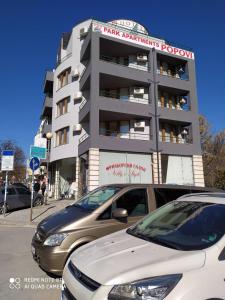 a parking lot with cars parked in front of a building at Park Apartments & Rooms Popovi in Sandanski
