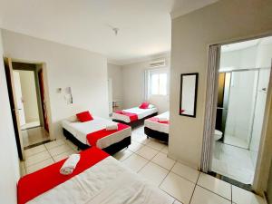 a hotel room with three beds and a mirror at Hotel Jardim do Cedro in Cedral