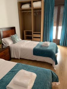 1 Schlafzimmer mit 2 Betten und blauen Vorhängen in der Unterkunft GAV Remedios 20 in Ronda