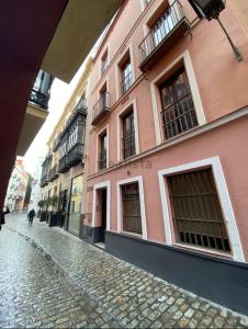 a pink building on a cobblestone street at piso exterior centro sevilla in Seville