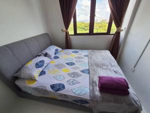a bed with a quilt on it in a room with a window at Maz Stayhouse in Alor Setar