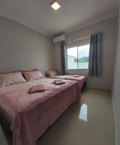 two beds in a room with a window at Curta Praia de Armação - Casa Girassol in Penha