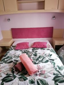 a bed with two pink pillows on top of it at Le pré vert in Campigny