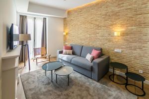 sala de estar con sofá y pared de ladrillo en Aquitania Home Suites en Sevilla