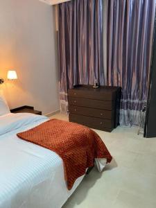 a bedroom with a bed and a dresser and a window at Metro Apartments in Lagos