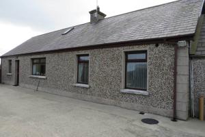 a building with three windows on the side of it at Jenny's Farm Cottage, Giant's Causeway in Dunseverick