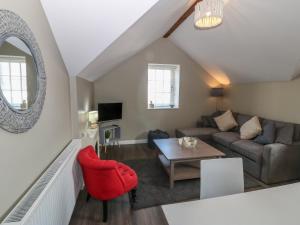 a living room with a red chair and a couch at Tan Bryn 1 in Aberdaron