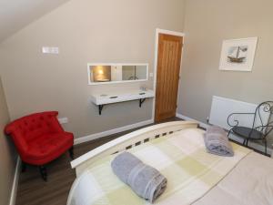 a bedroom with a bed and a red chair at Tan Bryn 1 in Aberdaron