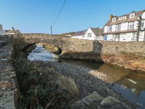 an old stone bridge over a river with houses at Tan Bryn 1 in Aberdaron