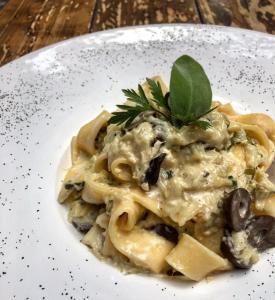 a plate of pasta with mushrooms and a green leaf at Pousada Castello Benvenutti in Bento Gonçalves
