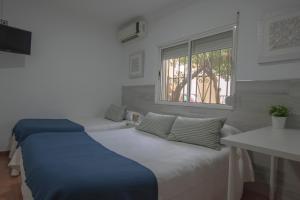 a bedroom with two beds and a window at PENSIÓN ISBEL in Málaga