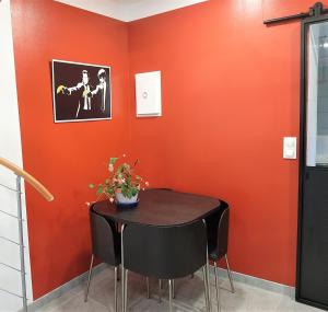 une table et des chaises dans une pièce avec un mur orange dans l'établissement Gîte de charme au coeur du vignoble de St Emilion, à Génissac