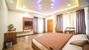 a hotel room with a bed and a tv at Aira Residency Kothagiri by Lexstays in Kotagiri
