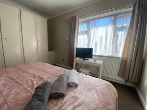 a bedroom with a pink bed and a desk and a window at 12 Harlesden Road close to ExCel in Romford