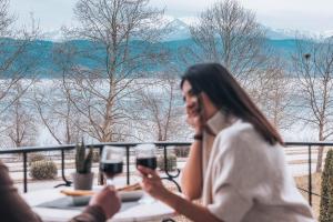 a woman sitting at a table with two glasses of wine at Akti Hotel Ioannina in Ioannina