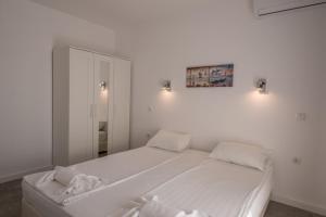 1 dormitorio blanco con 1 cama grande y espejo en Salia Apartments Tsarevo, en Tsarevo