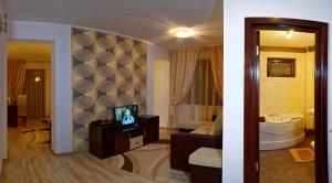 a bathroom with a television and a bathroom with a tub at Hotel boutique Garden Resort by Brancoveanu in Moieciu de Jos