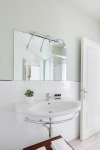 een witte badkamer met een wastafel en een spiegel bij Villa Maria Apartments in Cannobio