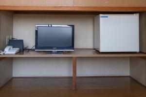 a computer monitor sitting on a shelf with a phone at Tabist Daibou Ichihara Mens Only in Ichihara