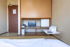 a bedroom with a bed and a desk and a tv at Tabist Daibou Ichihara Mens Only in Ichihara