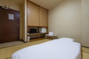 a bedroom with a bed and a door and a tv at Tabist Daibou Ichihara Mens Only in Ichihara