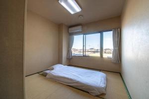 a small bedroom with a bed and a window at Tabist Daibou Ichihara Mens Only in Ichihara