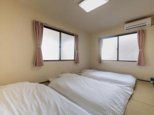 two beds in a room with two windows at Tabist Daibou Ichihara Mens Only in Ichihara