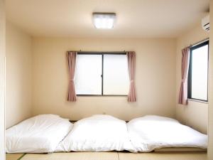 two beds in a room with a window at Tabist Daibou Ichihara Mens Only in Ichihara