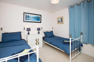 two beds in a bedroom with blue curtains at Lovely 2 bedroom apt in Ballater on the River Dee in Ballater