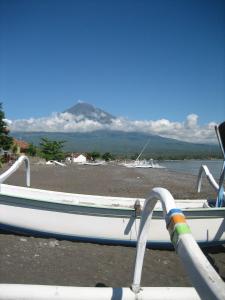 a boat sitting on the shore of a body of water at Lucky Paradise Bungalows on The Beach in Amed