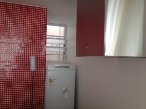 baño de azulejos rojos con nevera y espejo en Studio vista lateral mar perto de 3 praias e Wifi 250Mb, en Río de Janeiro